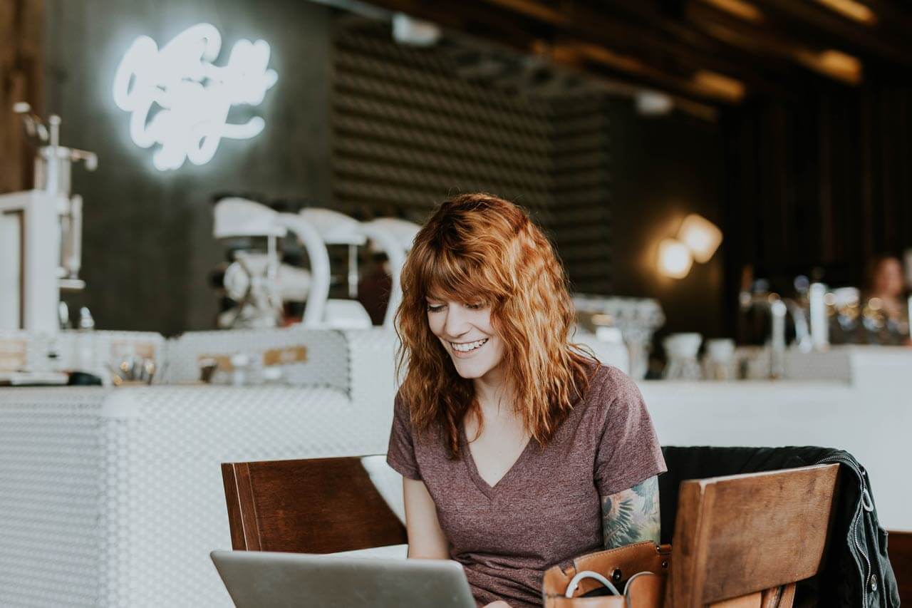 Junge Frau in einem Café an einem Laptop.